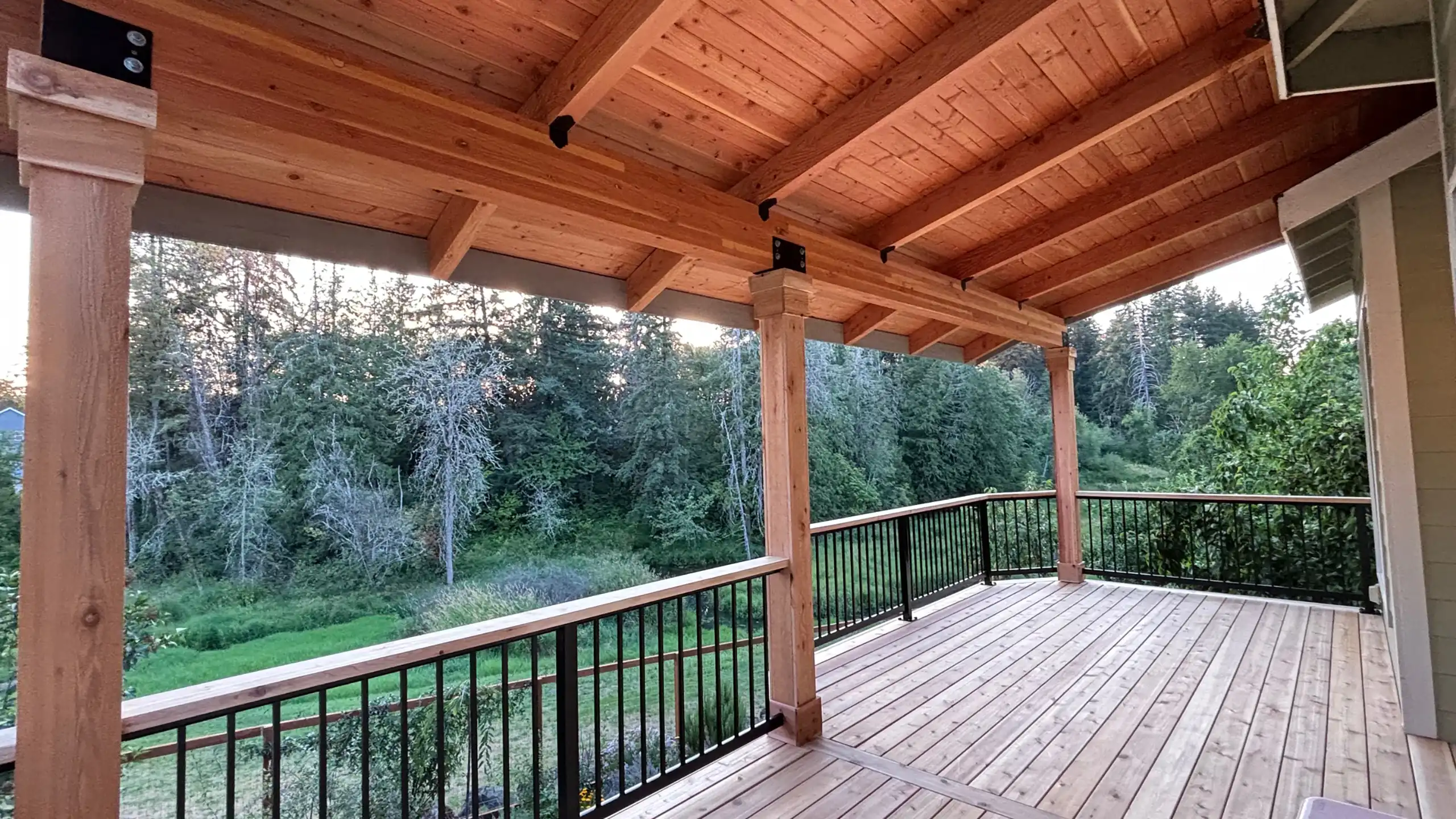 Cedar deck with an attached covered patio roof overlooking a wooded area.