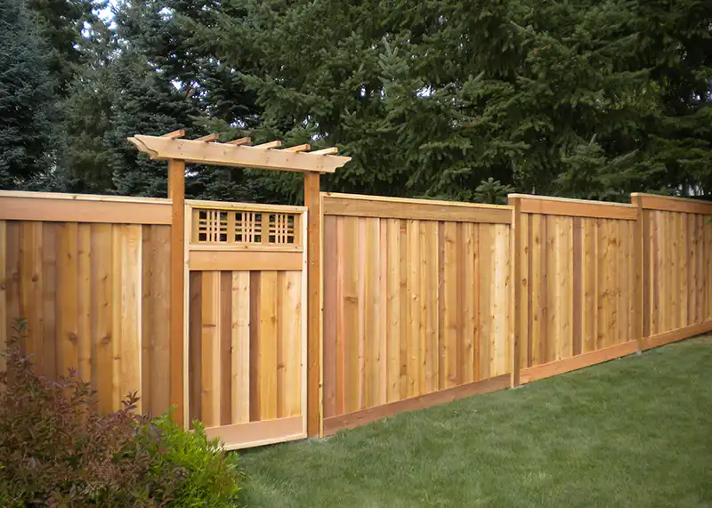 Arbor mounted on top of a cedar privacy fence in a residential yard.