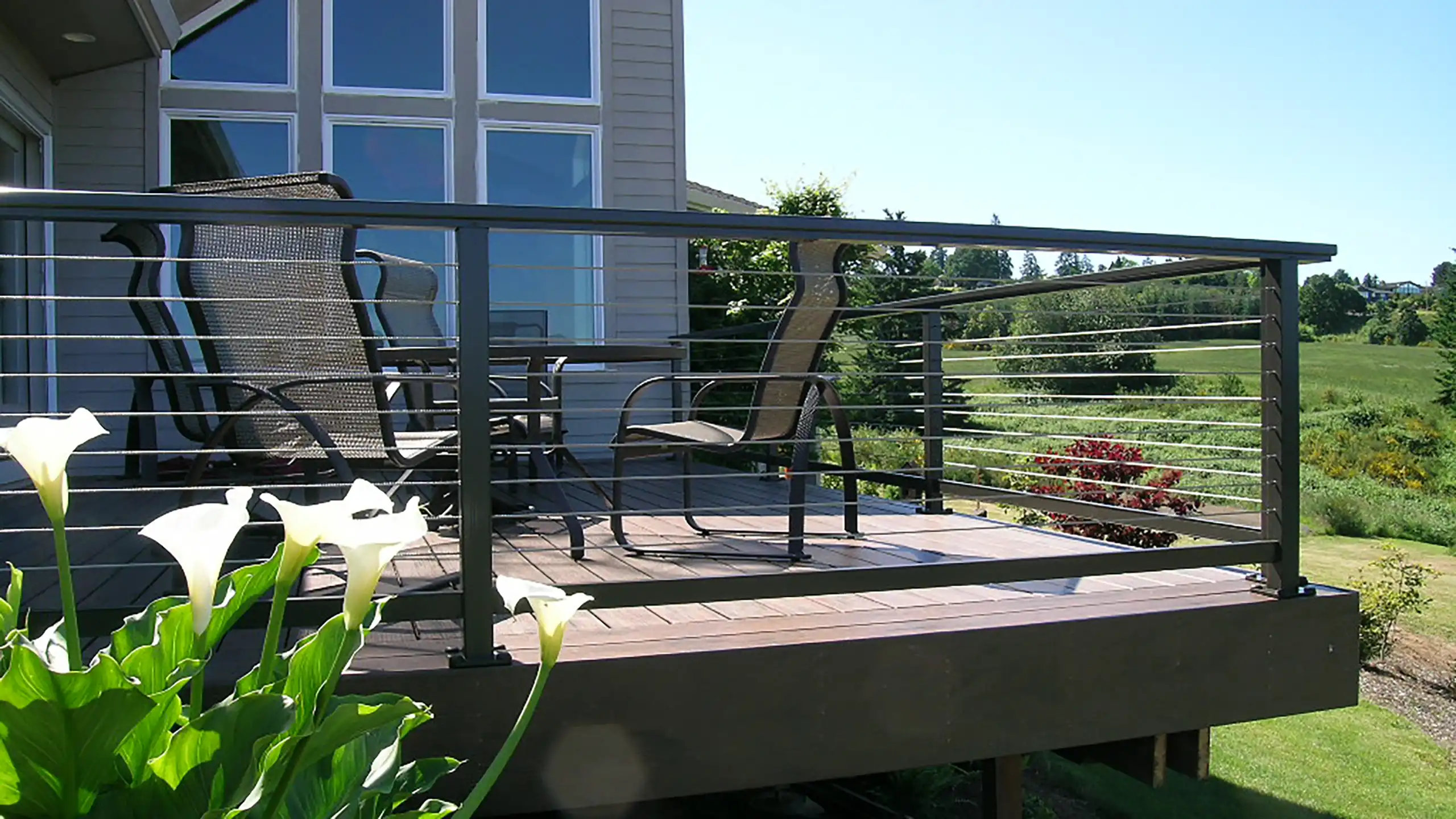 Composite deck with stainless steel cable railing and brown aluminum frame.