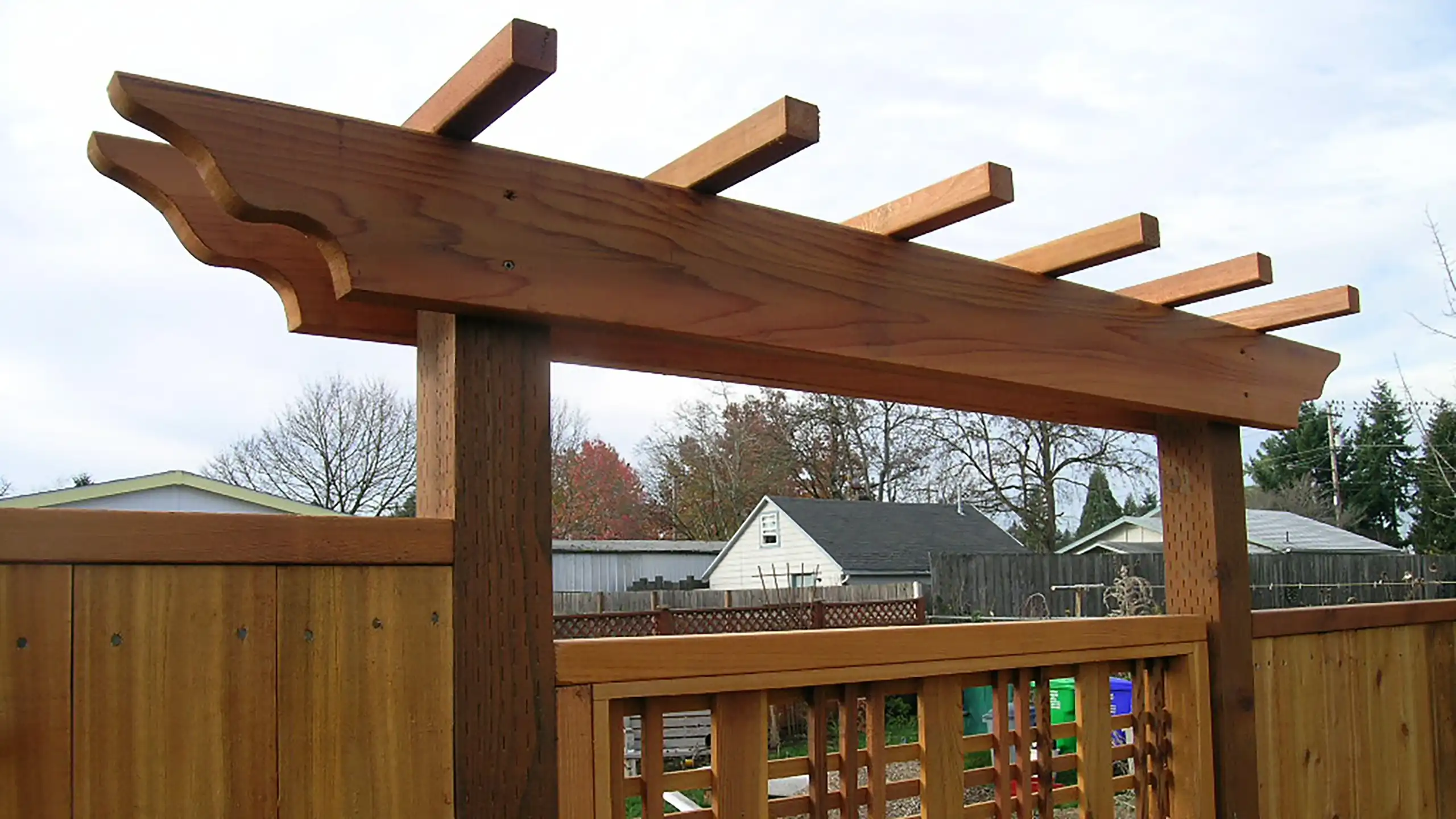 Straight wood arbor installed above a fence line in a residential yard
